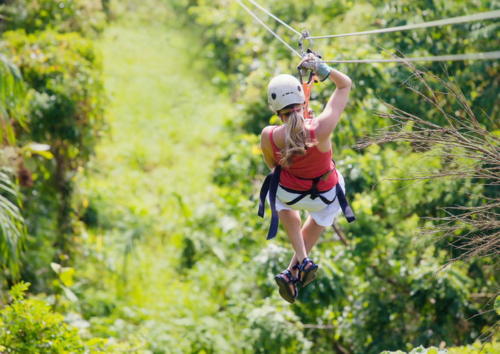Woman enjoying a fun zip line tour in the jungle while on vacation
